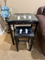 Two black lacquer nesting tables with inlaid figures