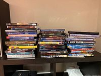 Three stacks of assorted DVD cases on shelf