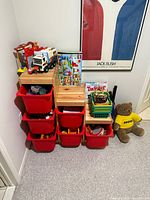 Full view of wooden storage unit with red bins and toys