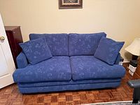 Front view of blue upholstered sofa bed with cushions