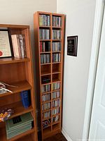 Full view of tall CD tower next to bookcase