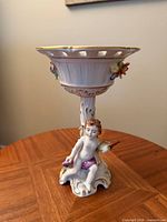 Front view of porcelain compote showing cherub and pierced rim