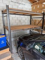 Full view of shelving unit in garage showing steel frame and two wooden shelves