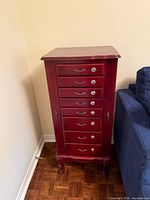 Full view of burgundy wood jewellery chest next to sofa