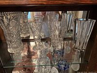 All four cut crystal vases on glass shelf