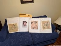 Four unframed matted prints on couch