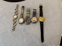Five watches laid out side by side on fabric surface