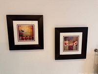 Both framed prints hanging side by side on wall