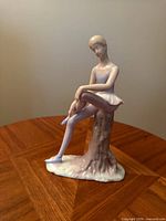 Front view of porcelain ballerina seated on stump