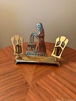 Front view showing entire brass Shabbat candle holder with woman lighting candles and two candle cups