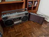 Front view of JVC boombox next to cassette case