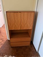 Front view of teak cabinet showing doors, open shelf, drawers