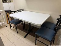 Full view of white melamine dining table with black metal base