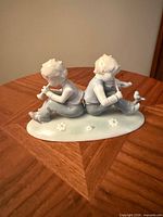 Front view of figurine showing two children back-to-back playing flutes