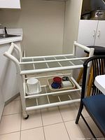 Full view of bar cart showing frame, two glass shelves, casters