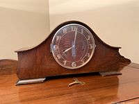 Front view of wooden tambour mantel clock with key