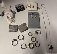 Overview of earrings on cards, rings and necklace