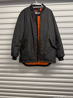 Full view of front of black bomber coat on hanger