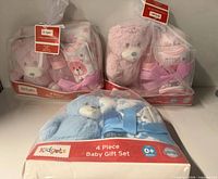 Front view of all three boxed baby gift sets: two pink, one blue