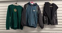 Three outerwear items hanging: Eagles jacket center, green hoodie left, black vest right