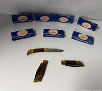 Seven blue Hanson Knife boxes and three knives displayed on white background