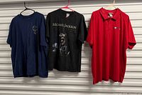 Three shirts on hangers: navy tee, Michael Jackson tee, red polo
