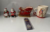 Group shot of all items: Santa & Mrs. Claus shakers, red sleigh dish, princess mug, packaged souvenir spoon