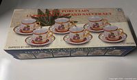 Top view of retail box showing images of six cup and saucer sets, product name