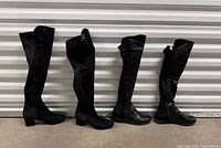 Four black over-the-knee boots standing side by side