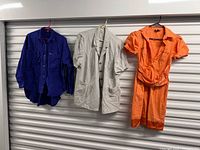 Three garments hanging: blue shirt, grey blazer, orange dress