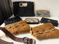 Group shot showing all eight items including handbag, wallets, shearling clutches and belt