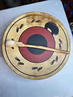 Front view of rawhide drum with indigenous motif and beater