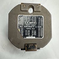 Front of closed compass showing maker plate and natural sines table