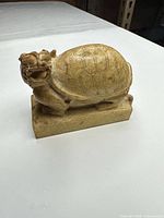 Front side view of carved turtle-dragon showing shell pattern and head detail