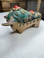 Left front view showing decorative leaf and floral motifs, horns, gold trim