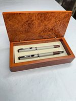 Open presentation box showing two beige metal ballpoint pens seated in cream insert