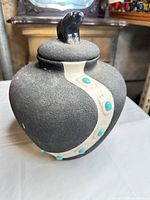 Front view of black ceramic jar showing cream accent and turquoise inlays