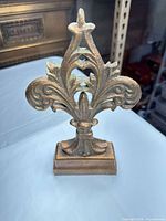 Front view of brass fleur-de-lis finial on base