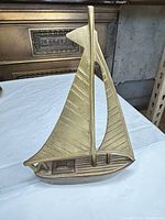 Front angled view of brass sailboat showing sail texture and cabin