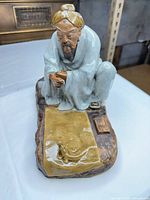 Front view of celadon porcelain scholar figurine on rock base