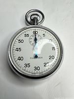 Front view of stopwatch showing dial, hands, numerals, brand, and sub-dial