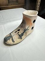 Angled view showing painted desert scene, boot shape and drainage holes