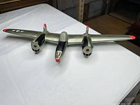 Front view showing twin-engine layout, cockpit, insignia, and red accents