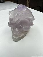 Three-quarter front view of lavender quartz skull with serpent carving