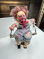 front view of horror zombie cloth doll on metal stand showing facial gore and outfit