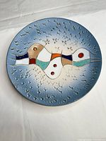 Front view of large blue decorative ceramic wall plate with abstract multicolour motif and textured surface