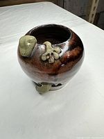 Top angled view of vase showing brown glaze, green sculptural appliqués and interior