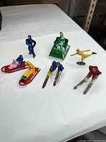 All eight winter sport toy figures and sleds grouped on table