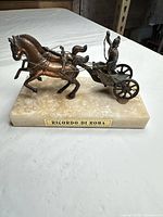 Front view of bronze chariot sculpture on marble base with plaque visible