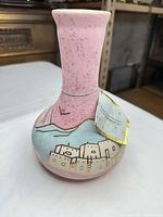 Overall view of pink ceramic vase with pueblo motif and hang tag